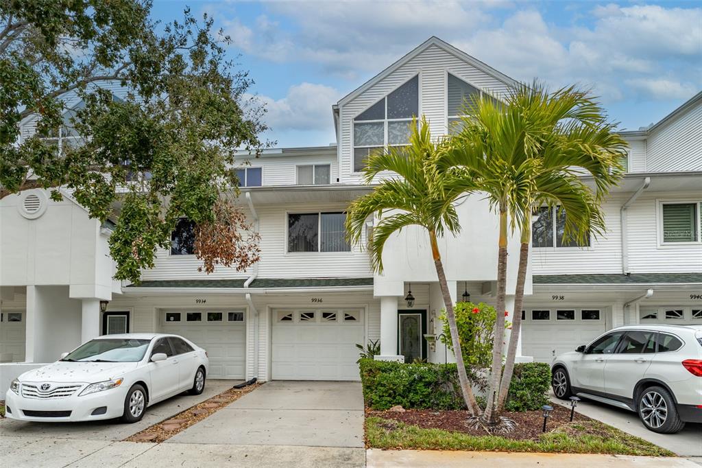 A row of white multi-story townhomes with attached garages and a palm tree in front — 9936 INDIAN KEY TRAIL UNIT 22, SEMINOLE, FL