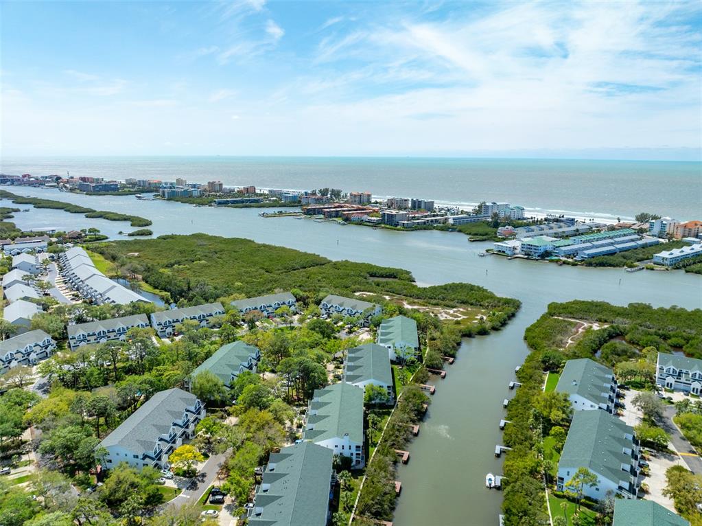 An aerial view shows multi-story residential buildings surrounded by lush trees and a coastal waterway — 9936 INDIAN KEY TRAIL UNIT 22, SEMINOLE, FL