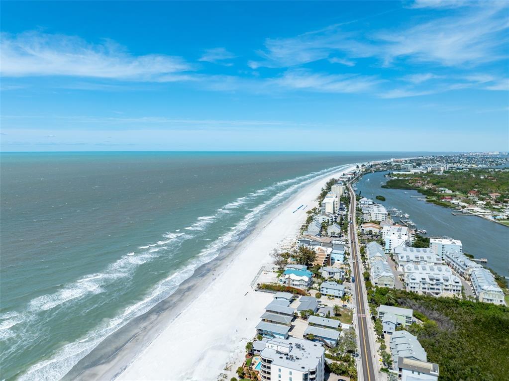An aerial view of a white sand beach, ocean, and coastal buildings along a road — 9936 INDIAN KEY TRAIL UNIT 22, SEMINOLE, FL
