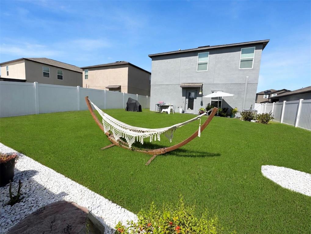A backyard features a hammock on a wooden stand, a white fence, and a house — 6470 BACK FORTY LOOP, ZEPHYRHILLS, FL