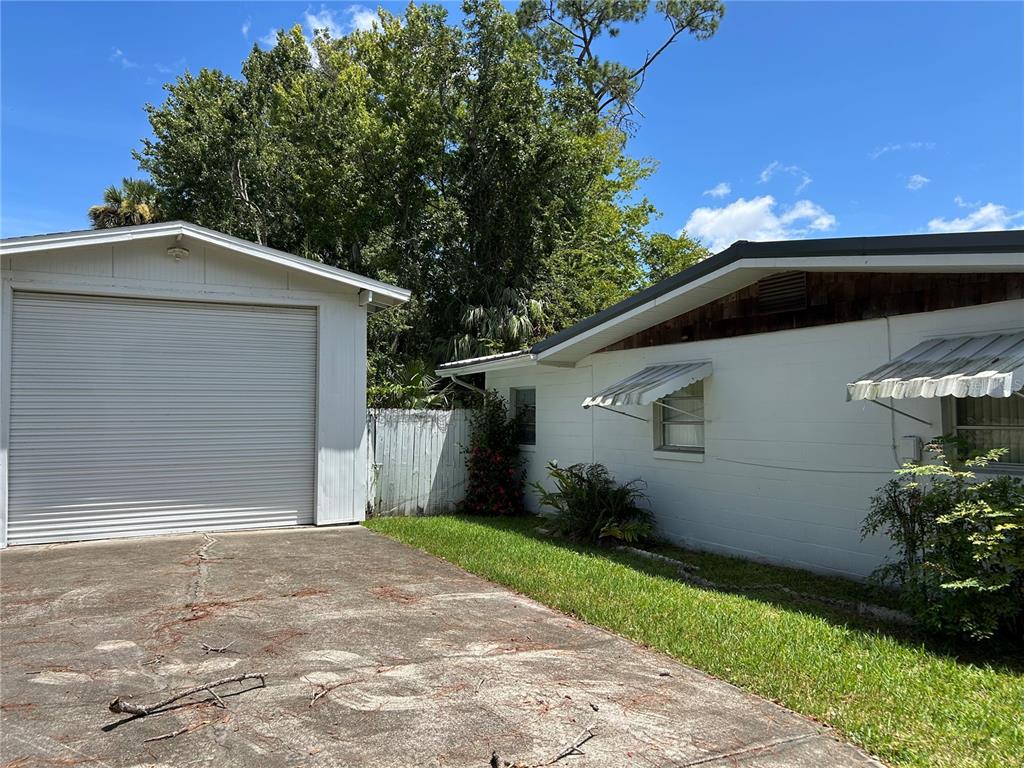 A white detached garage sits next to a white house with metal window awnings — 24121 ARMADILLO ROAD, ASTOR, FL