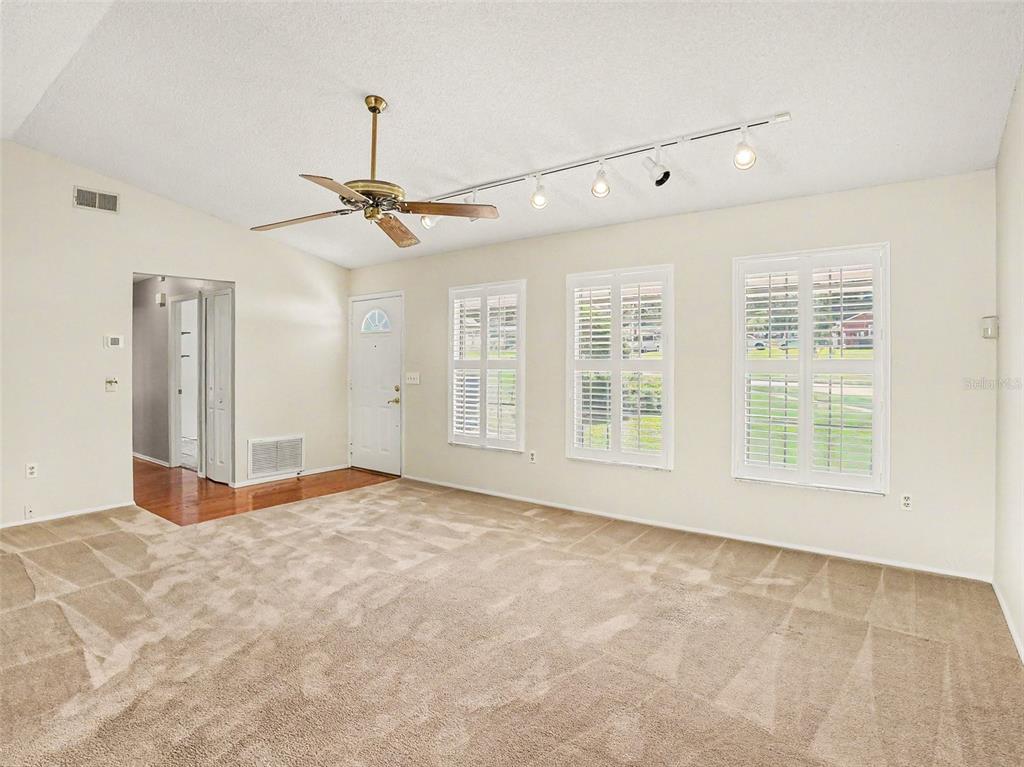 A living room with beige carpet, a ceiling fan, and track lighting — 7207 IMMOKALEE COURT, ORLANDO, FL