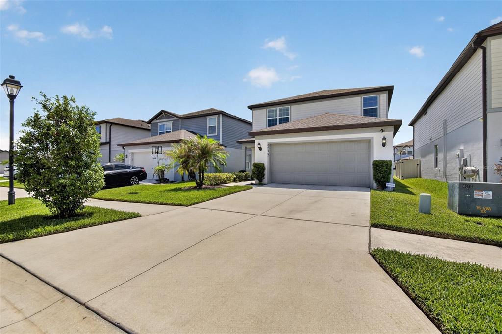 A two-story suburban house with a gray garage door and a concrete driveway — 6579 RYESTONE WAY, WESLEY CHAPEL, FL