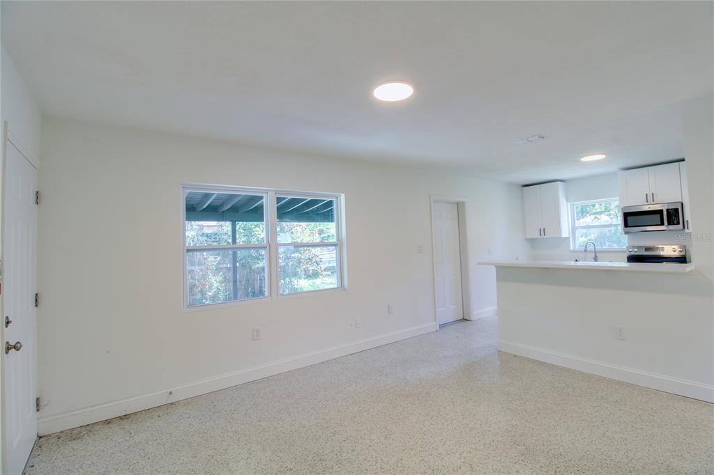 An open-concept living area features white walls, terrazzo flooring, and a kitchen with white cabinets — 1618 INDIANA AVENUE UNIT 1616, WINTER PARK, FL