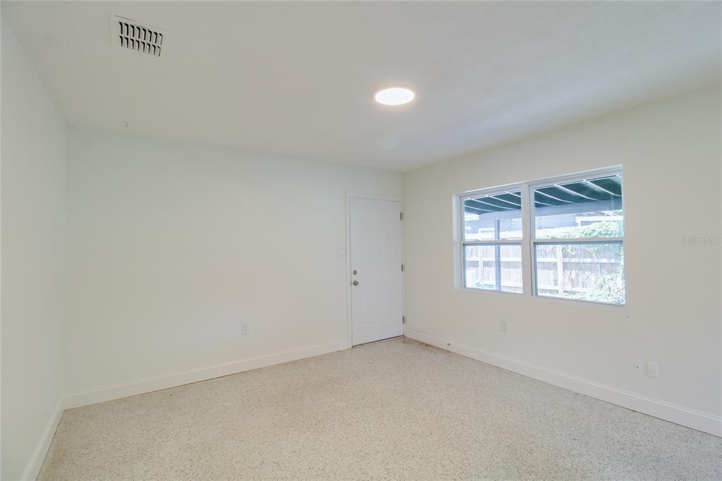 A bright room features white walls, a light-colored carpet, a single door, and a window — 1618 INDIANA AVENUE UNIT 1616, WINTER PARK, FL