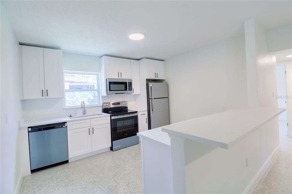 A kitchen with white cabinets, stainless steel appliances, and a breakfast bar — 1618 INDIANA AVENUE UNIT 1616, WINTER PARK, FL
