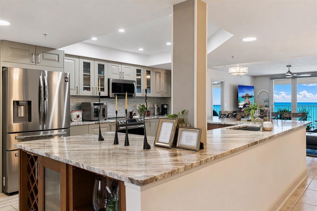 A modern kitchen features light gray cabinets, stainless steel appliances, and patterned stone countertops — 2055 S ATLANTIC AVENUE UNIT 705, DAYTONA BEACH SHORES, FL