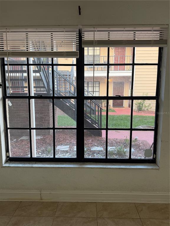 A view through a window shows a staircase and a neighboring apartment building exterior — 21026 VOYAGER BOULEVARD UNIT 4, LAND O LAKES, FL