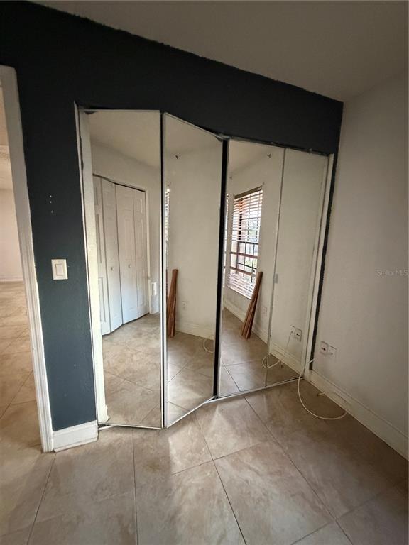 A room features a large, multi-panel mirrored closet door and light-colored tile flooring — 21026 VOYAGER BOULEVARD UNIT 4, LAND O LAKES, FL