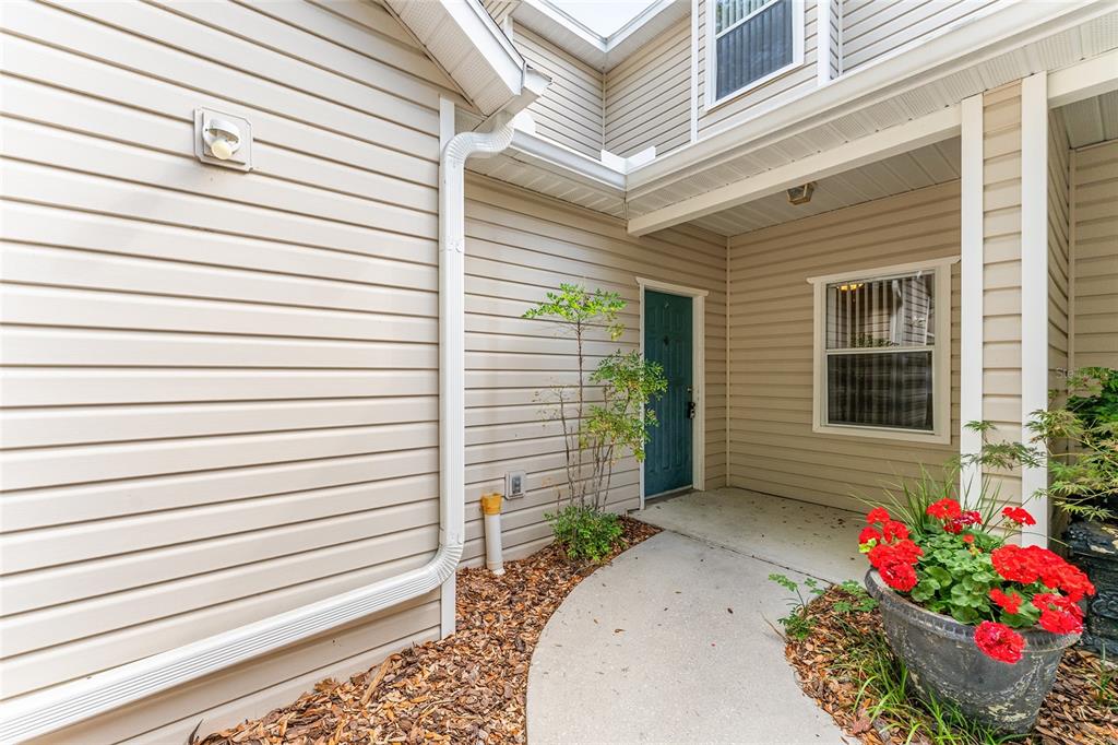 A beige-sided home exterior features a concrete walkway leading to a blue front door — 4700 SW ARCHER ROAD UNIT B-13, GAINESVILLE, FL