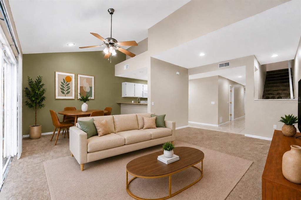 A living room with beige carpet, a tan sofa, a coffee table, and a dining area — 4700 SW ARCHER ROAD UNIT B-13, GAINESVILLE, FL