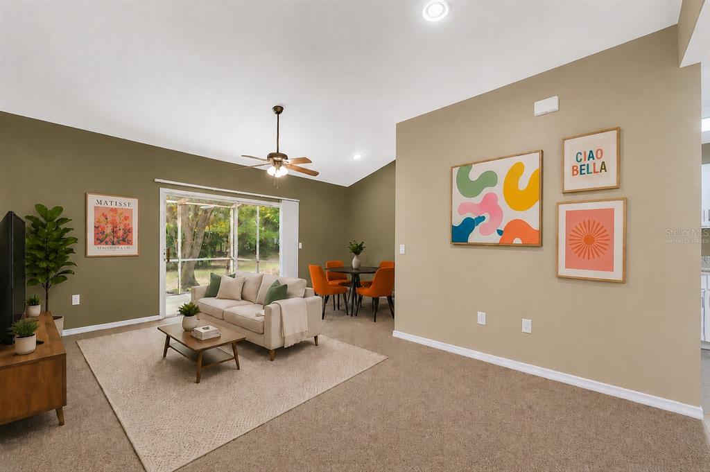 A living room with beige carpet, olive green walls, a sofa, and a dining set — 4700 SW ARCHER ROAD UNIT B-13, GAINESVILLE, FL