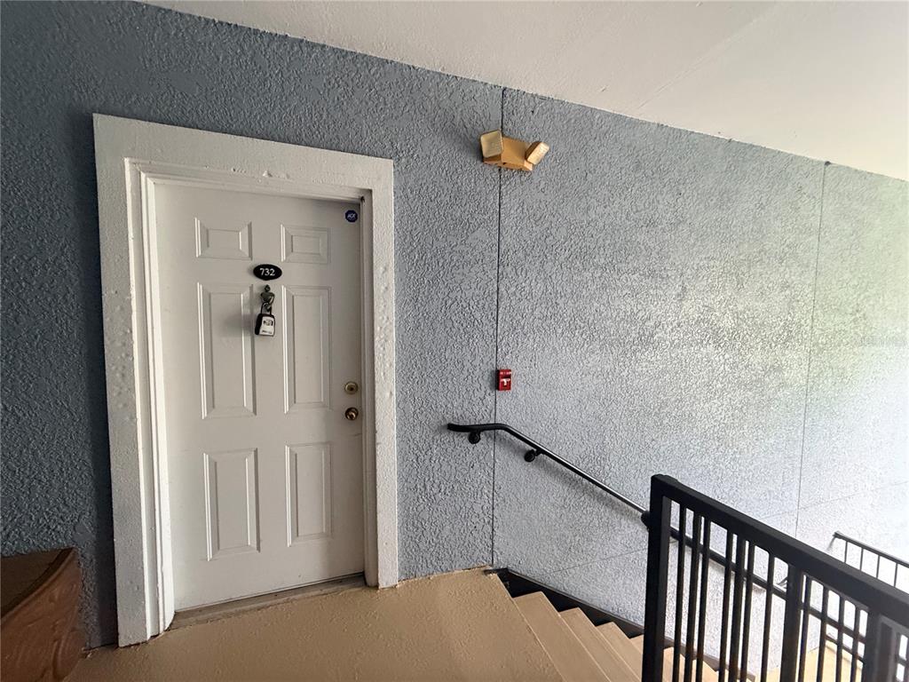 A white apartment door with a lockbox is located at the top of a staircase — 3621 CONROY ROAD UNIT 732, ORLANDO, FL