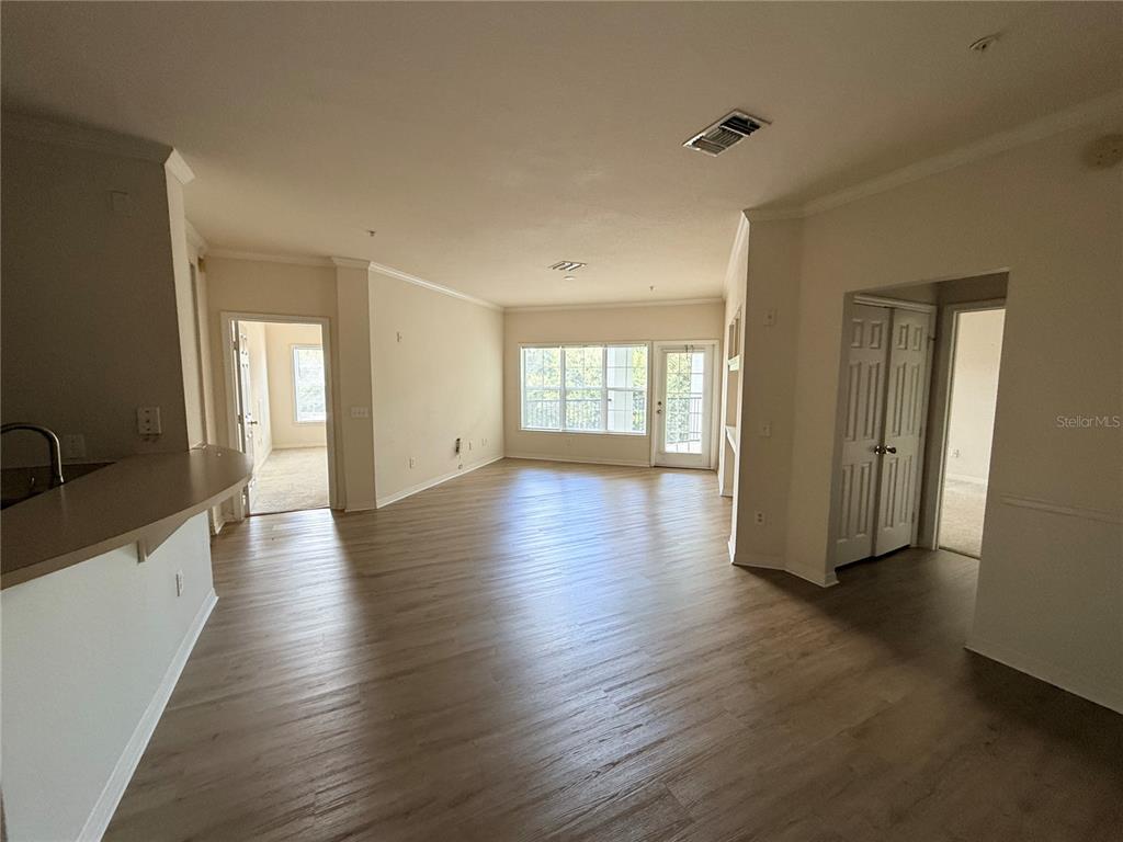 An open-concept living area features light-colored walls, wood-look flooring, and a sliding glass door — 3621 CONROY ROAD UNIT 732, ORLANDO, FL