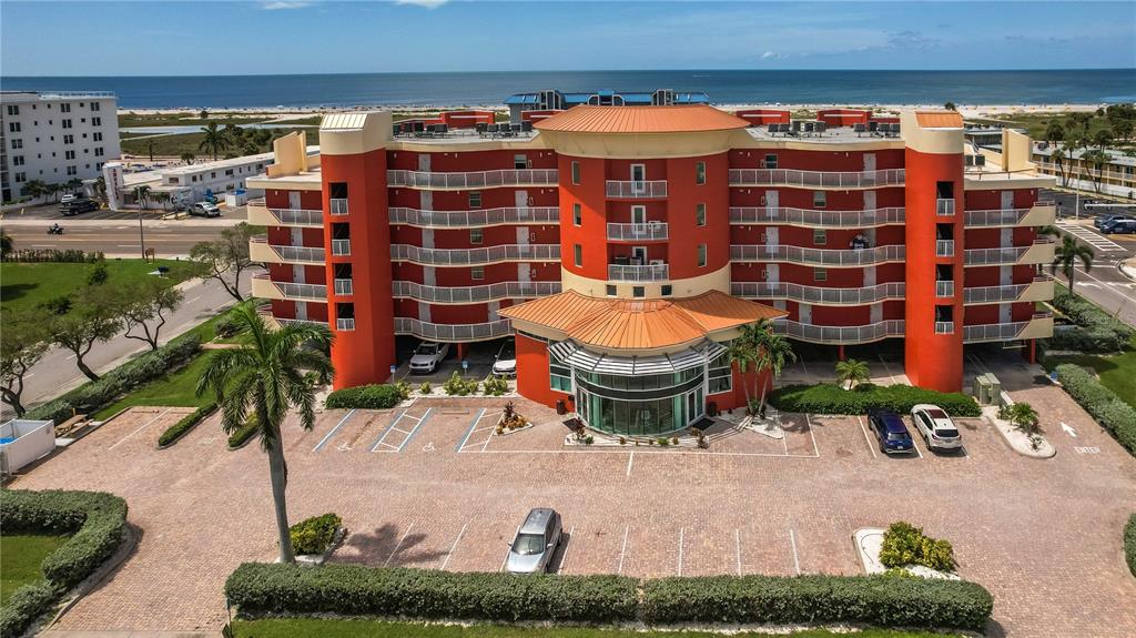 An aerial view of a sandy beach with scattered umbrellas and a hotel in the distance — 11605 GULF BOULEVARD UNIT 503, TREASURE ISLAND, FL