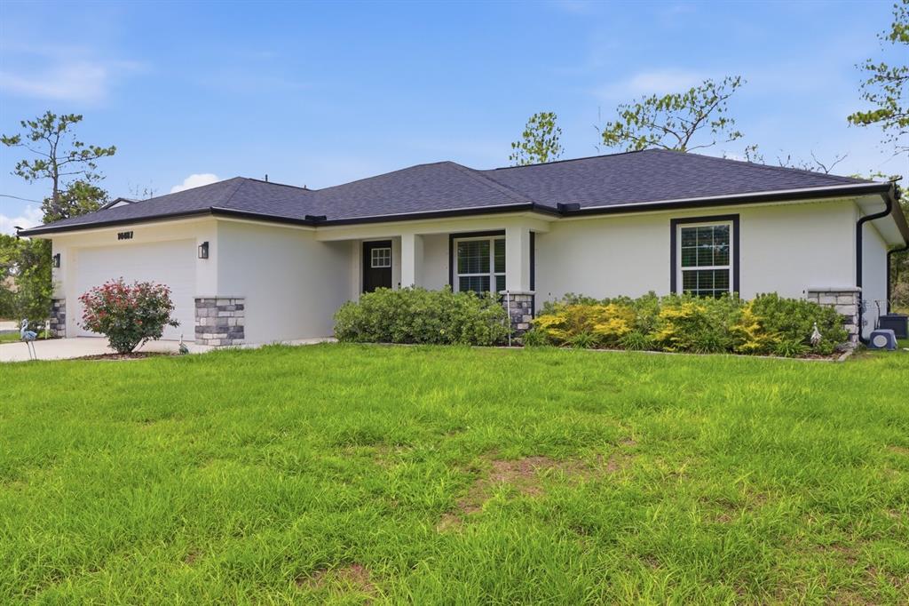 A single-story house with a white stucco exterior, dark roof, and a two-car garage — 14487 GOLDENEYE ROAD, WEEKI WACHEE, FL