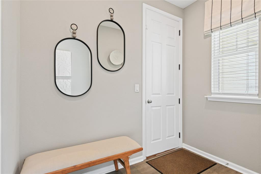 An entryway features a beige bench, two oval wall mirrors, a white door, and blinds — 5862 SUNLIT BEND WAY, APOLLO BEACH, FL