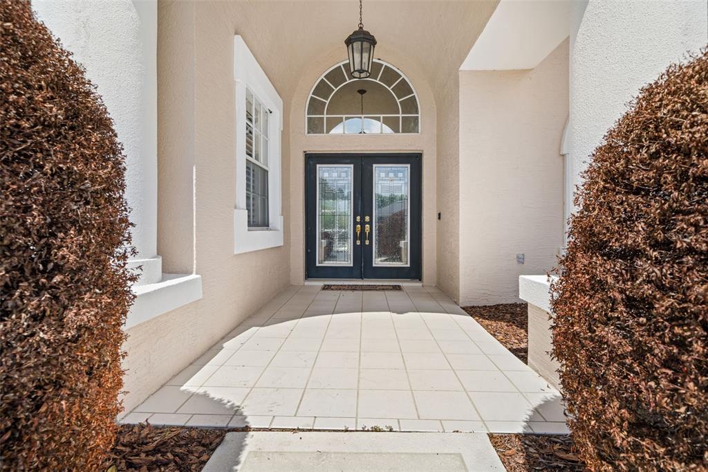 A front entryway features a tiled porch, double doors, and a decorative arched transom window — 8405 MAYBELLE DRIVE, WEEKI WACHEE, FL