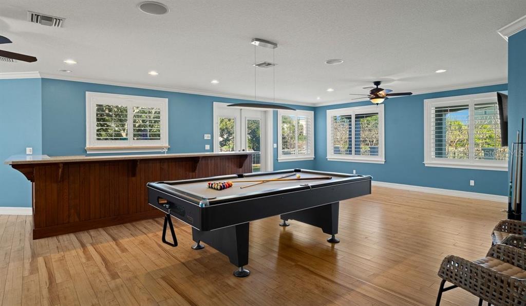 A game room features a pool table, a wooden bar, and blue walls with windows — 2 MAR AZUL N, PONCE INLET, FL