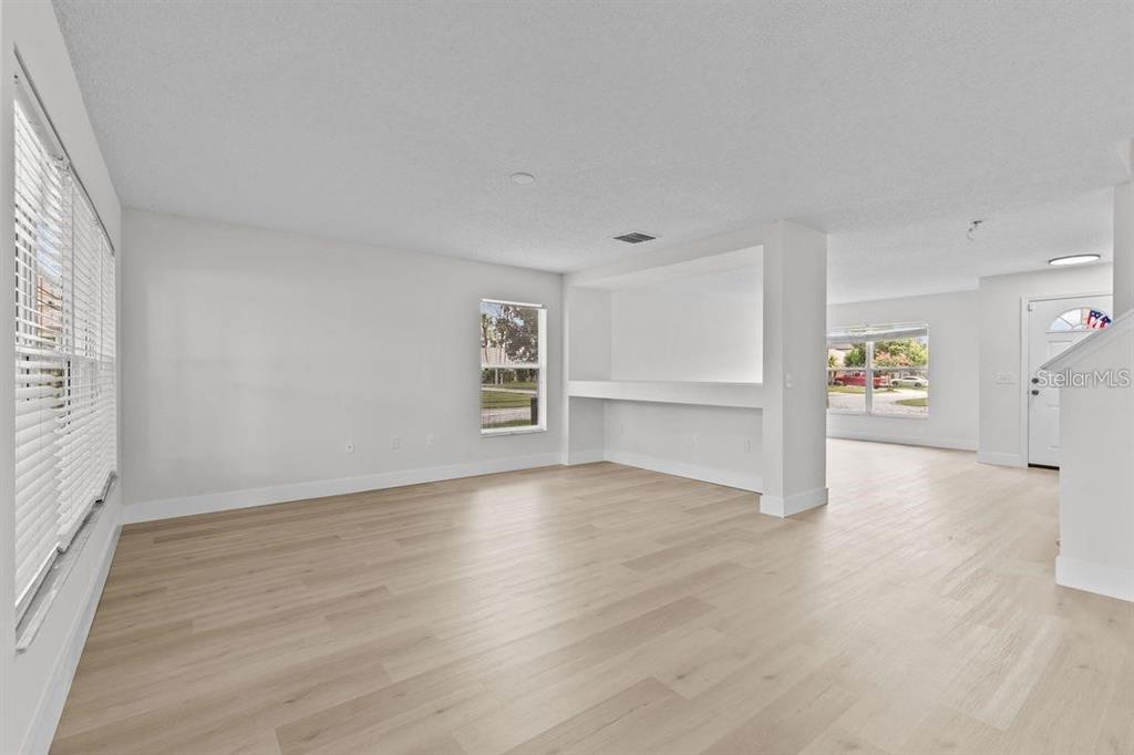 A bright living room features light wood-look flooring, white walls, and a built-in wall niche — 1537 MORNING STAR DRIVE, CLERMONT, FL