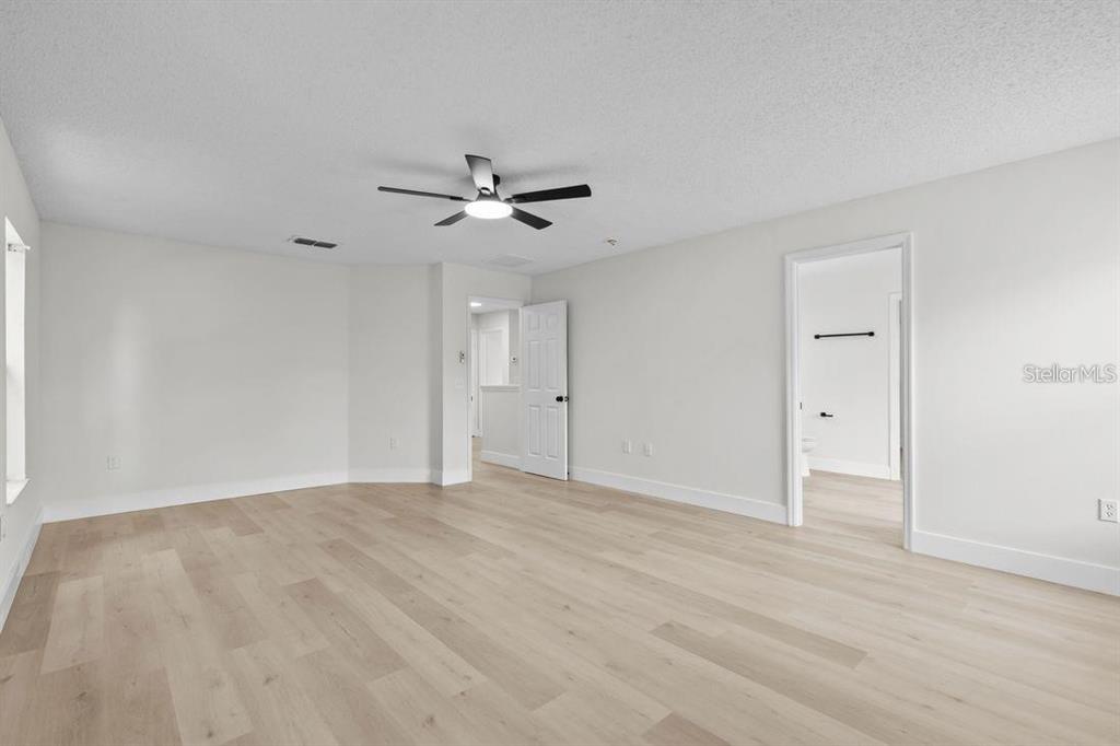 A bright, empty room features light wood-look flooring, white walls, and a ceiling fan — 1537 MORNING STAR DRIVE, CLERMONT, FL
