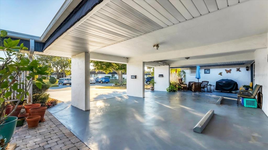A covered carport with a concrete floor, support pillars, and outdoor seating area — 3823 GLEN OAKS DRIVE E UNIT 83, SARASOTA, FL