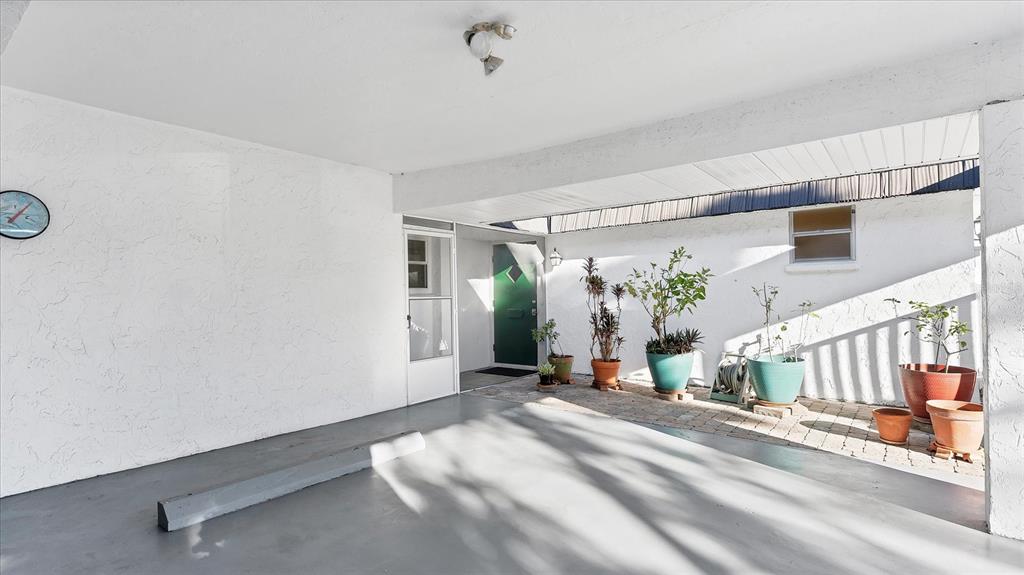 A covered carport with a concrete floor, a brick patio area, and several potted plants — 3823 GLEN OAKS DRIVE E UNIT 83, SARASOTA, FL