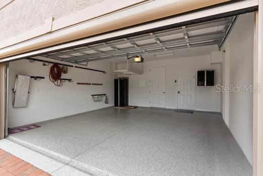 An open garage with a speckled epoxy floor, white walls, and two interior doors — 1108 SAWGRASS DRIVE, WINTER HAVEN, FL