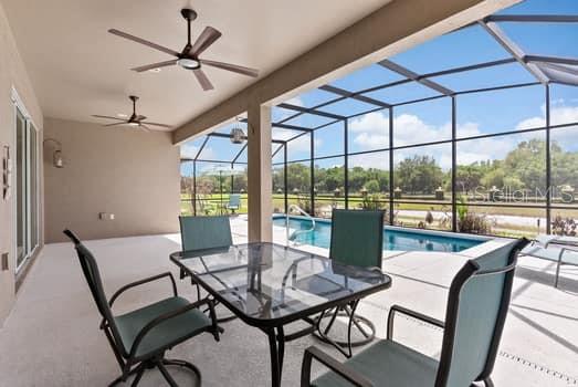 A covered patio with a dining set overlooks a screened-in swimming pool and backyard — 1108 SAWGRASS DRIVE, WINTER HAVEN, FL
