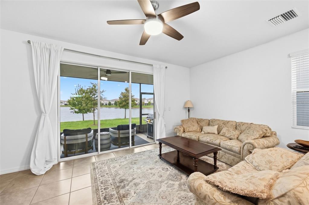 A living room features tile floors, a patterned rug, floral sofas, and a sliding glass door — 369 MANGROVE SHADE CIRCLE, APOLLO BEACH, FL