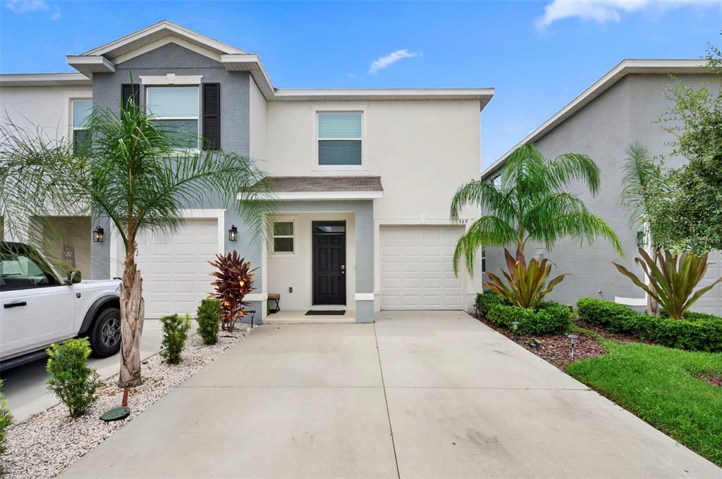 A two-story townhouse with a concrete driveway, two garage doors, and a black front door — 369 MANGROVE SHADE CIRCLE, APOLLO BEACH, FL