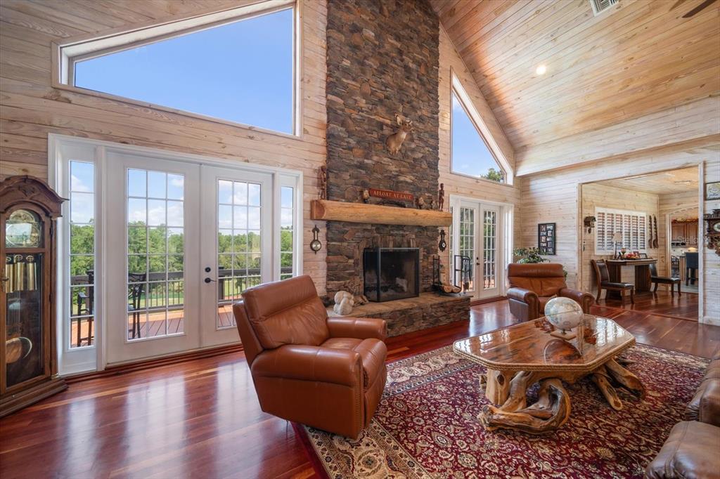 A living room features a stone fireplace, vaulted wood ceilings, and large glass doors — 7650 N WHIPPOORWILL TERRACE, HERNANDO, FL