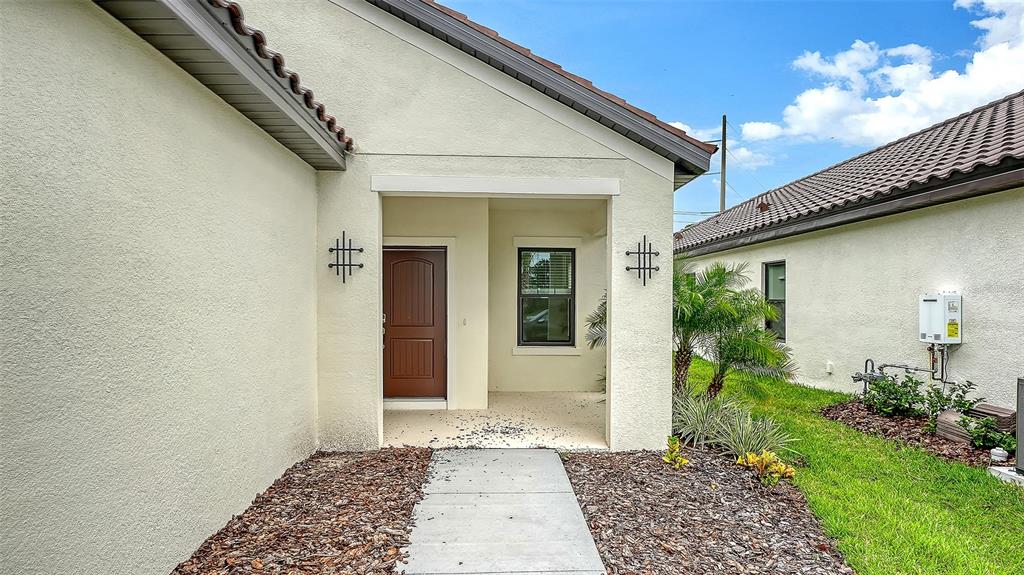 The exterior of a house features a brown front door, a concrete walkway, and landscaping — 333 POTENZA LOOP, NOKOMIS, FL