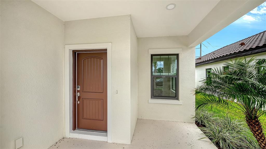 A covered entryway features a brown front door, a window, and a concrete porch floor — 333 POTENZA LOOP, NOKOMIS, FL