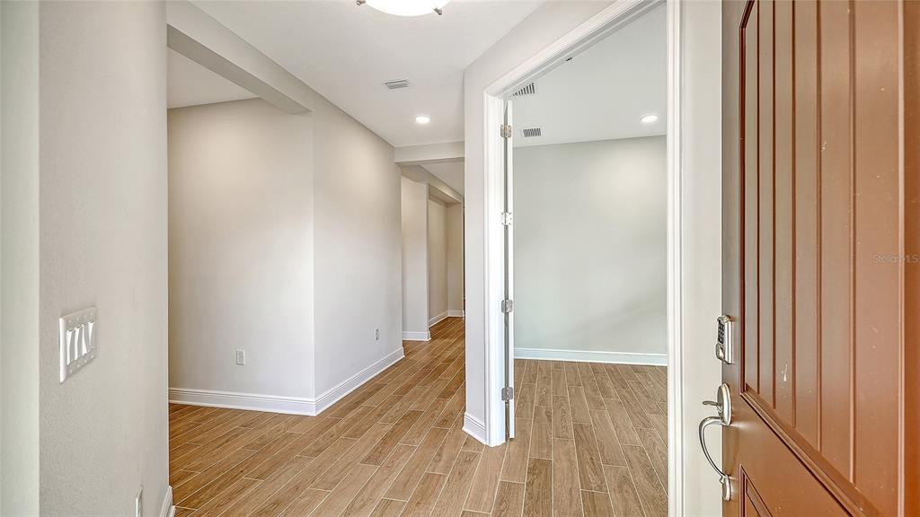 An entryway with wood-look tile flooring leads to an open room through a doorway — 333 POTENZA LOOP, NOKOMIS, FL