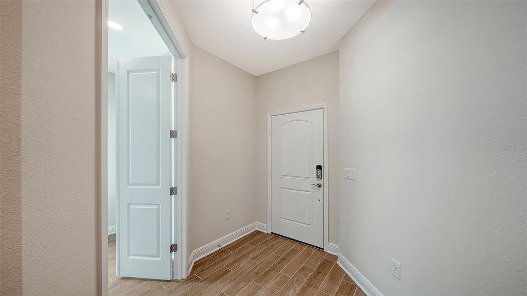 A bright entryway features wood-look tile flooring, a white door, and a flush-mount ceiling light — 333 POTENZA LOOP, NOKOMIS, FL