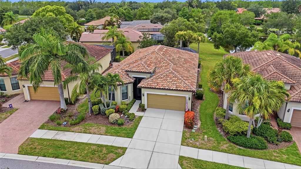 An aerial view shows three suburban houses with tiled roofs and palm trees in Florida — 2543 ARUGULA DRIVE, NORTH PORT, FL