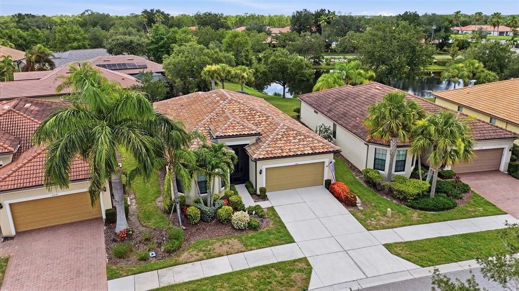 An aerial view shows a suburban house with a tiled roof, garage, and palm trees — 2543 ARUGULA DRIVE, NORTH PORT, FL
