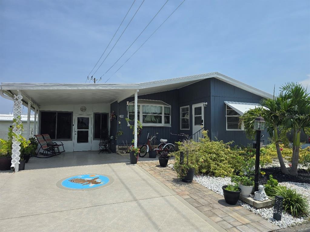A single-story house at night features purple exterior accent lighting, a carport, and landscaping — 5316 53RD AVENUE E UNIT L11, BRADENTON, FL