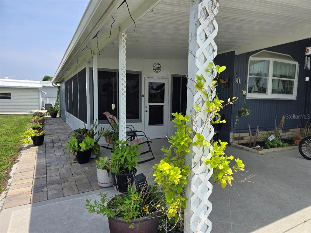 A blue mobile home features a covered carport, a concrete driveway, and a landscaped front yard — 5316 53RD AVENUE E UNIT L11, BRADENTON, FL