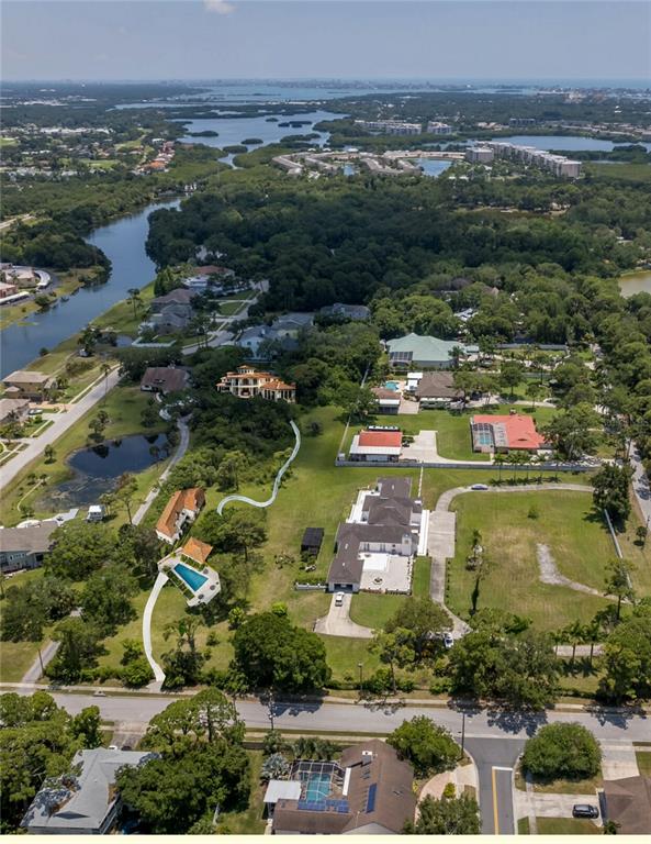 An aerial view shows several houses with swimming pools surrounded by trees and a waterway — 8181 98TH STREET, SEMINOLE, FL
