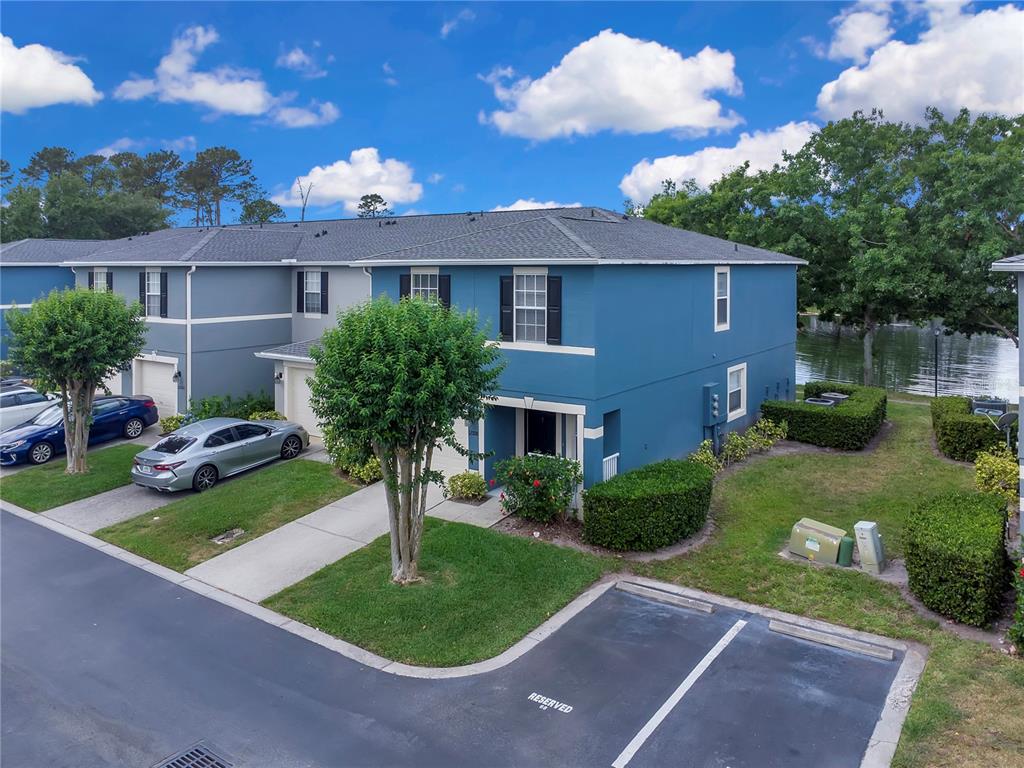 A blue two-story townhouse with a driveway, parking spaces, and a nearby lake — 12928 LEXINGTON SUMMIT STREET, ORLANDO, FL