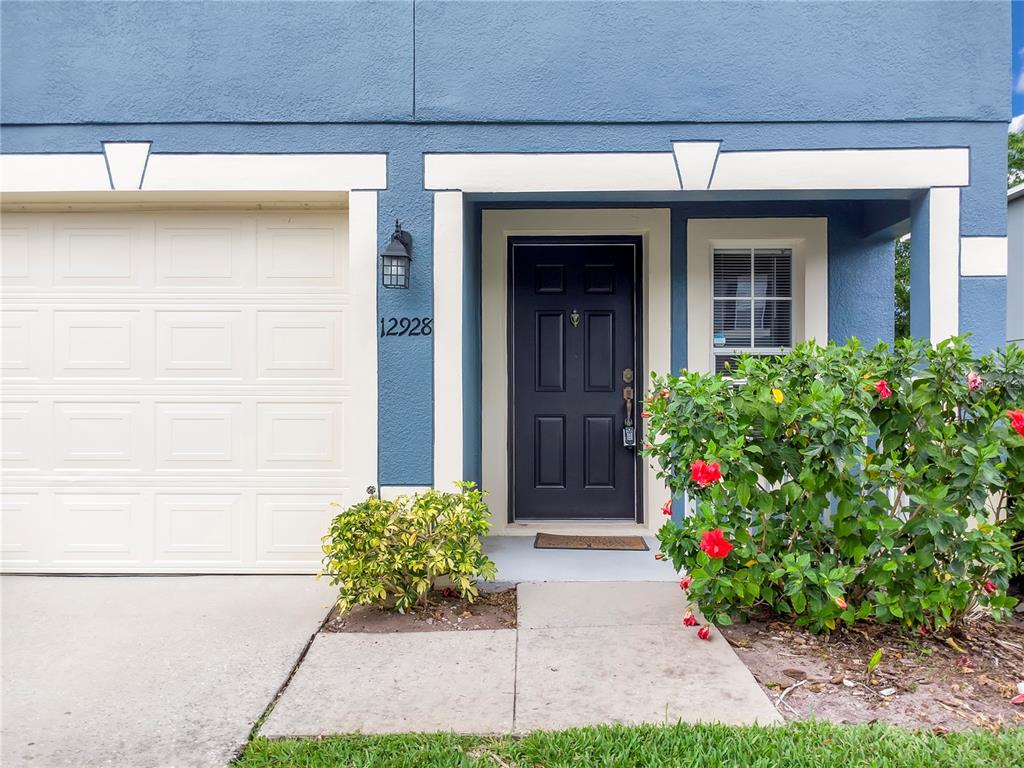 The exterior of a blue house features a garage, a dark front door, and landscaping — 12928 LEXINGTON SUMMIT STREET, ORLANDO, FL