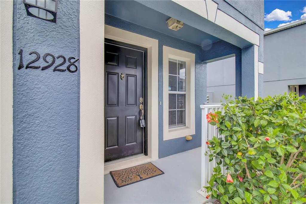 A blue exterior entryway features a black front door, a house number, and a small bush — 12928 LEXINGTON SUMMIT STREET, ORLANDO, FL