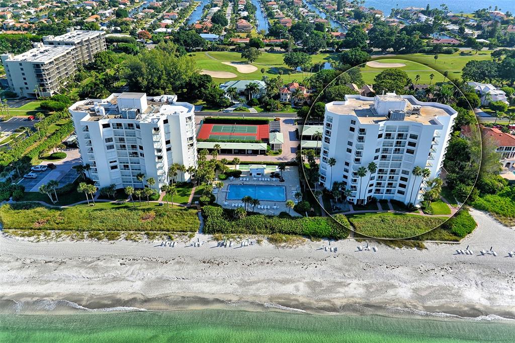 An aerial view shows two beachfront condominium towers with a swimming pool and tennis courts — 1000 LONGBOAT CLUB ROAD UNIT 304, LONGBOAT KEY, FL