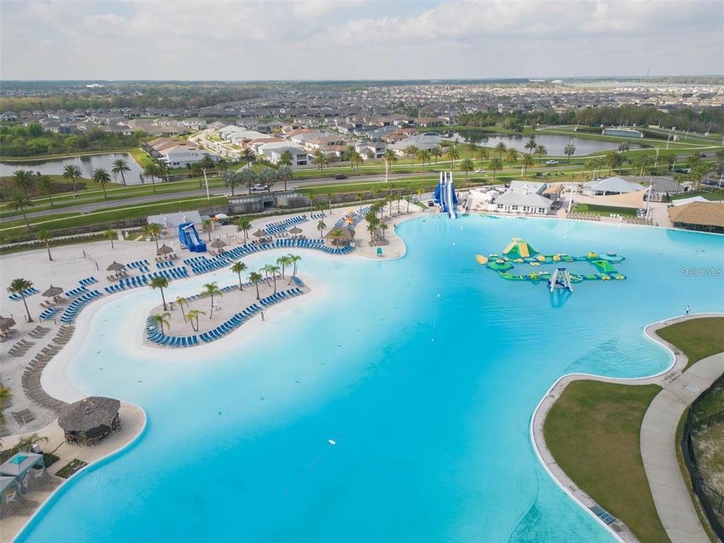 An aerial view of a large turquoise swimming lagoon with an island and water slides — 8377 CLAW GLADES LOOP, WESLEY CHAPEL, FL