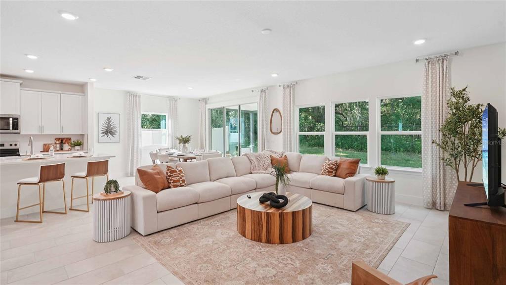 An open-concept living room features a large sectional sofa, a round wooden coffee table, and kitchen — 11269 DUCKLING WAY, WEEKI WACHEE, FL