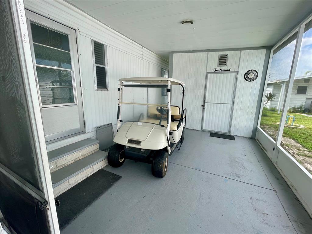 A golf cart is parked on the concrete floor of a screened-in porch — 34645 CAMPHOR DRIVE N, PINELLAS PARK, FL