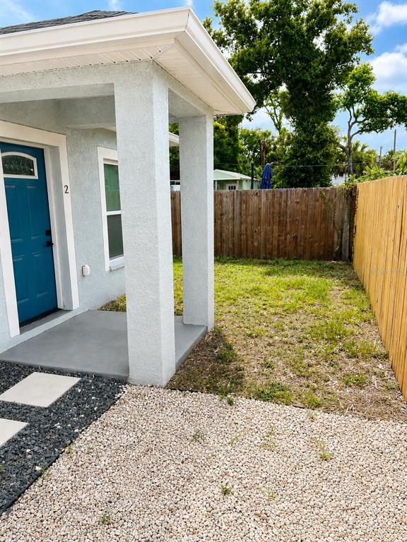A blue front door with a number two sits under a covered porch beside gravel — 1710 W NORTH B STREET UNIT 2, TAMPA, FL