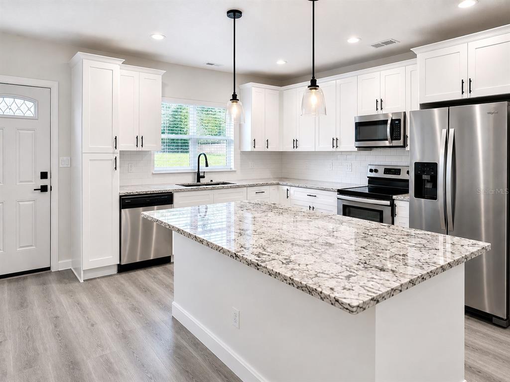 A modern kitchen features white cabinets, granite countertops, stainless steel appliances, and a central island — 1710 W NORTH B STREET UNIT 2, TAMPA, FL